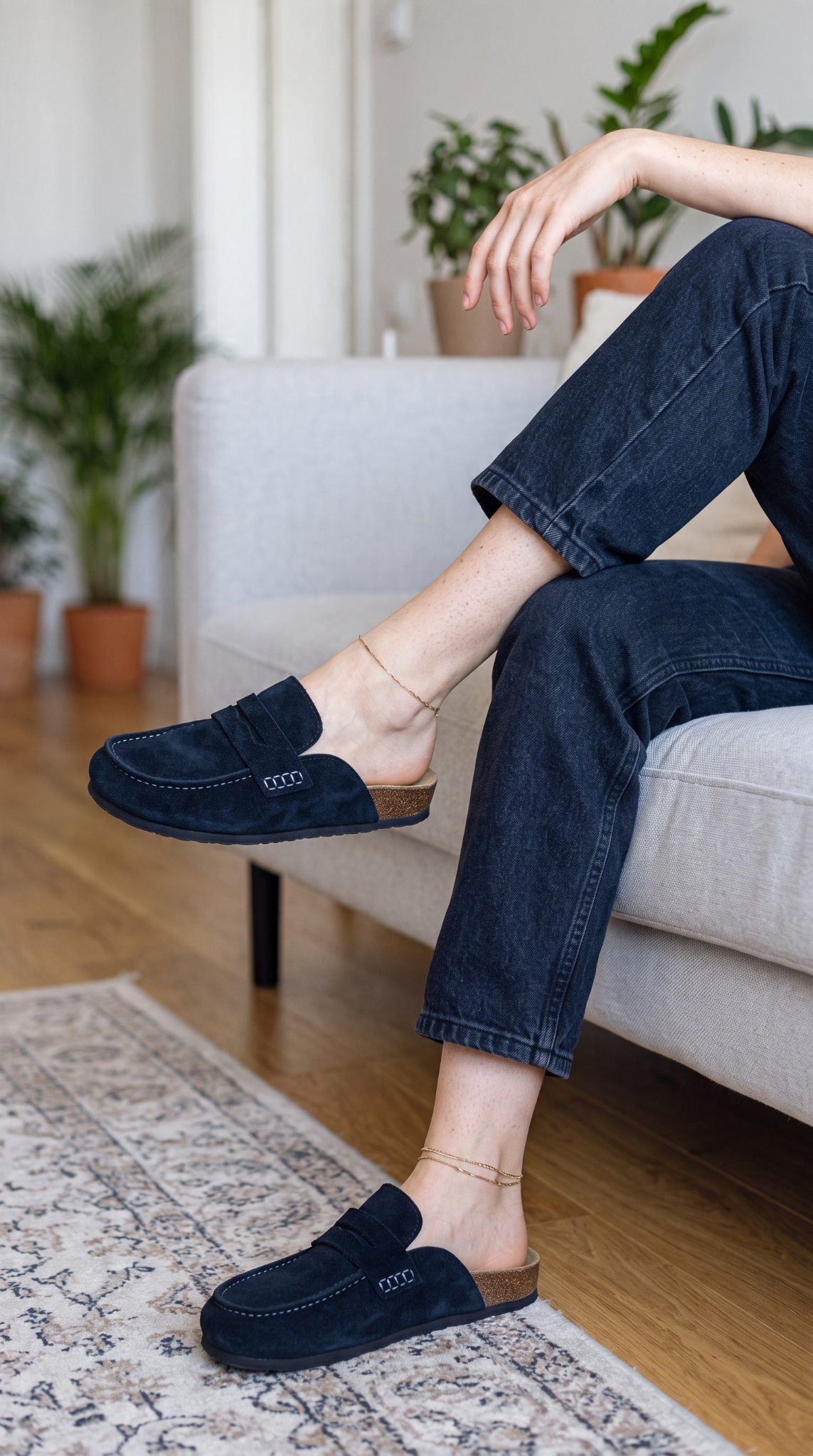Mules Avern Prestige portées avec un jean foncé sur un canapé