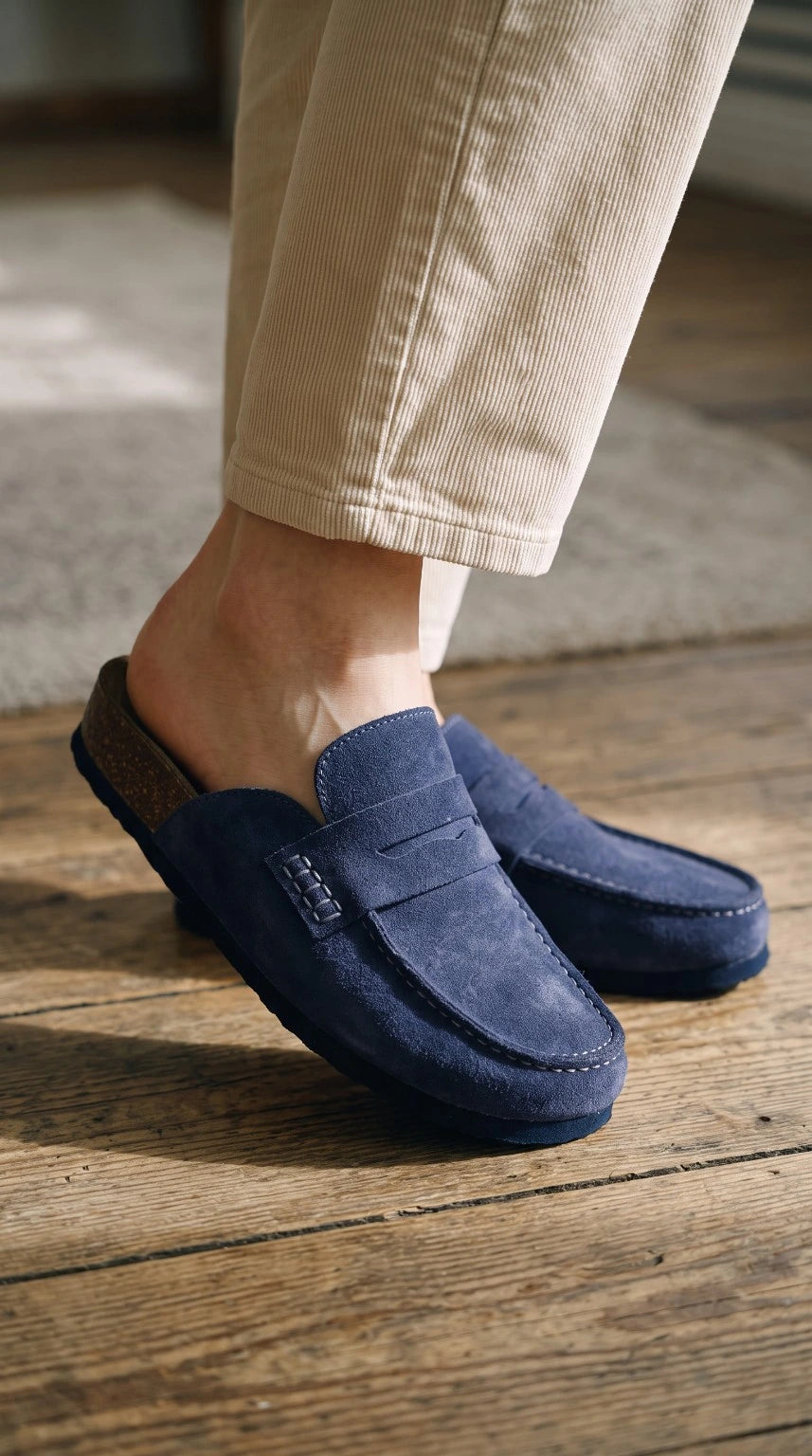 Avern Deep Navy, mules en croûte de cuir bleu profond portées sur un parquet ensoleillé